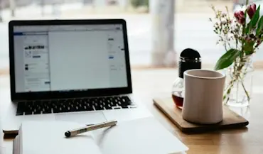 Un ambiente de estudio con un ordenador, un cuaderno y una taza